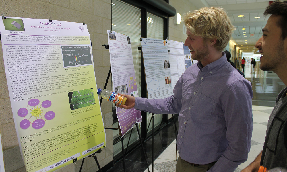 Profile of two male students looking at a poster and talking.