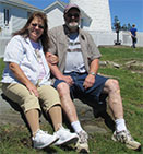 Jan Miller sitting with her husband outdoors and looking at the camera.