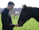 Profile view of Dr. Strong touching the nose of a horse to his right.