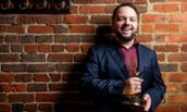 Photo of JMU alum Justin Lenart holding his Emmy