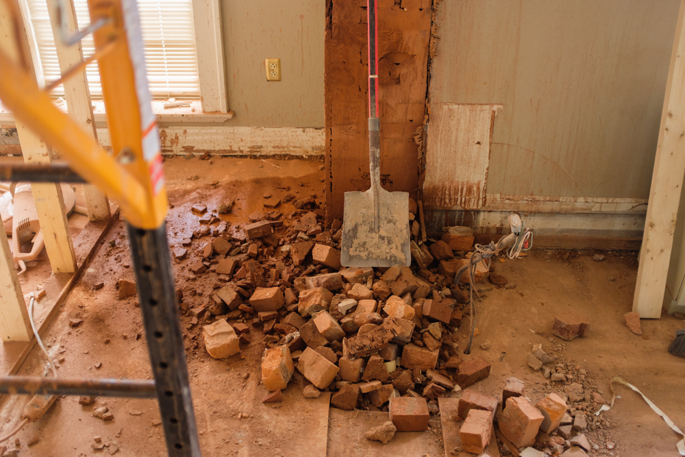 a shovel on top of torn down brick in a room being renovated