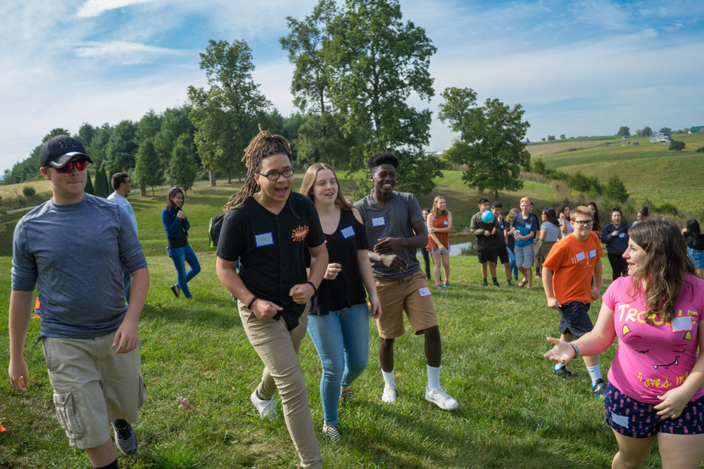 students running and laughing in a field on a sunny day