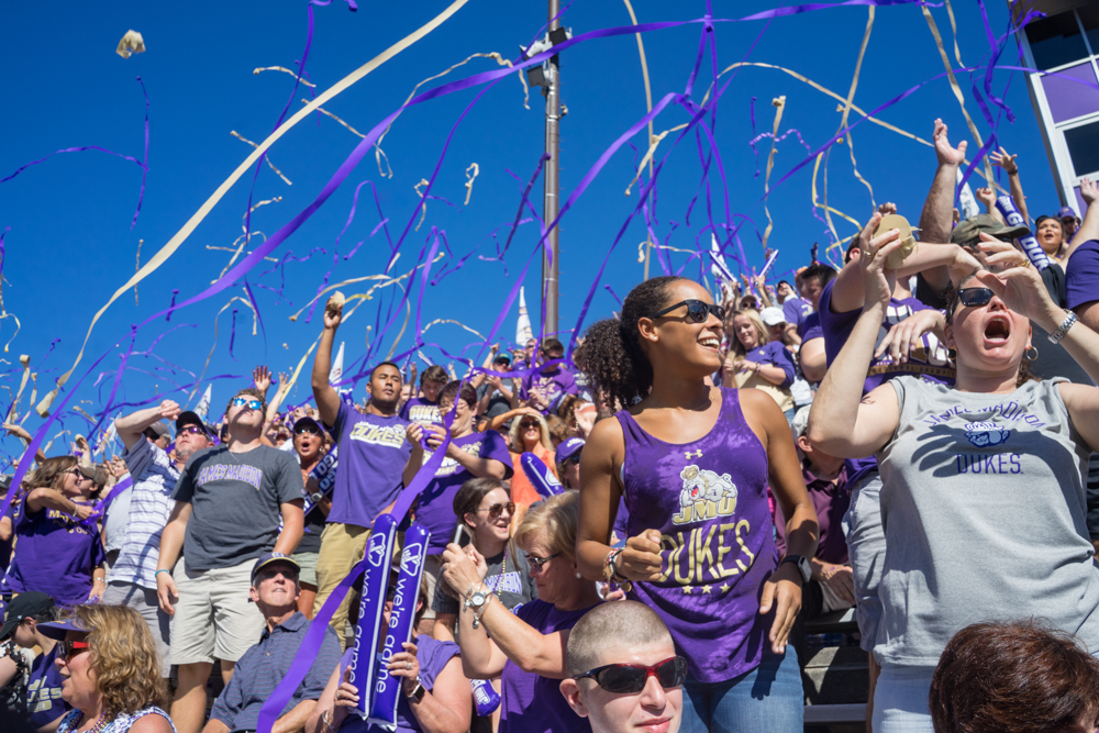 people cheering in the stands at a football game throwing streamers