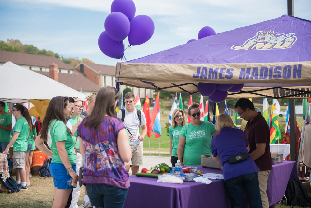 people gathered around outside at a JMU pop up tent and table