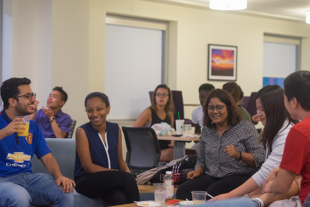 Students sitting in a lounge smiling and laughing. 