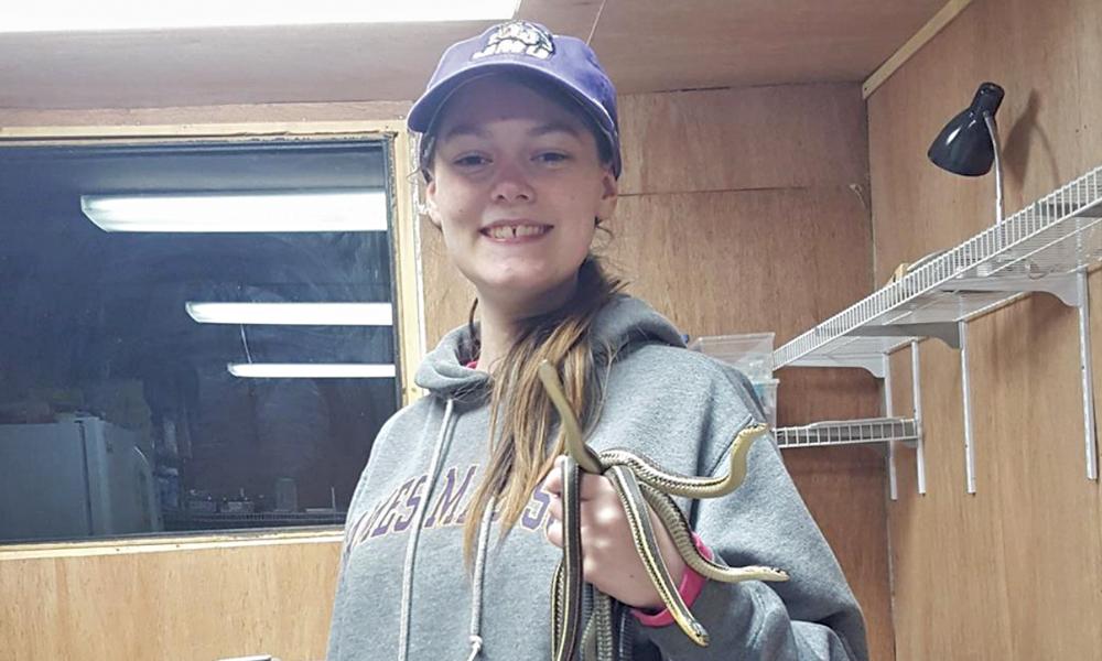 Biology student Shannon Richard holding several snakes