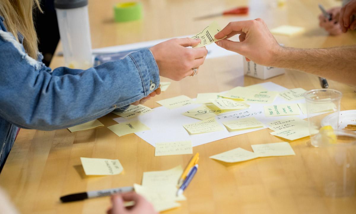 Close up of hands exchanging written-on sticky notes.