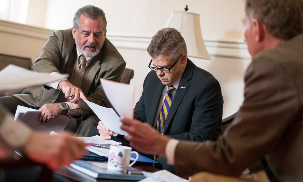 Kirk Cox looking at papers with man on either side