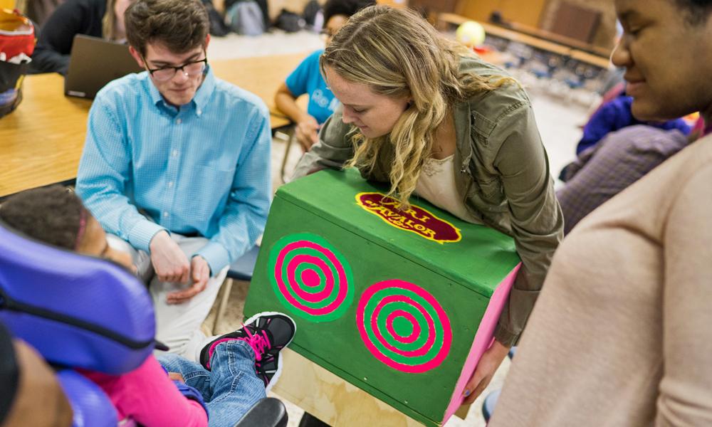 College-age students share musical instrument with child