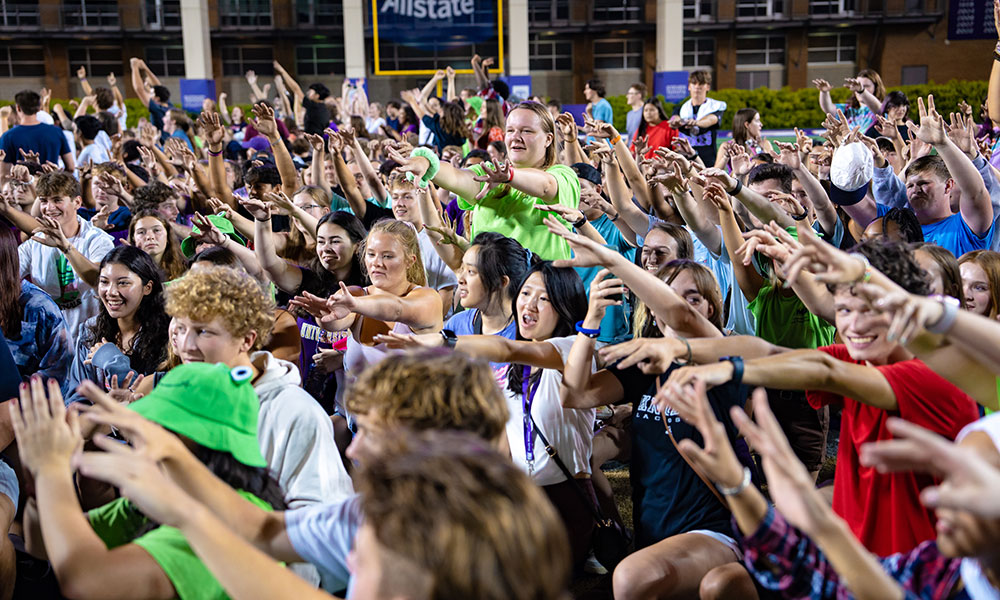 Students raise their hands together in a stadium