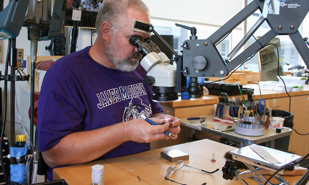 Mark Rooker uses a microscope to work on the MoonArk project