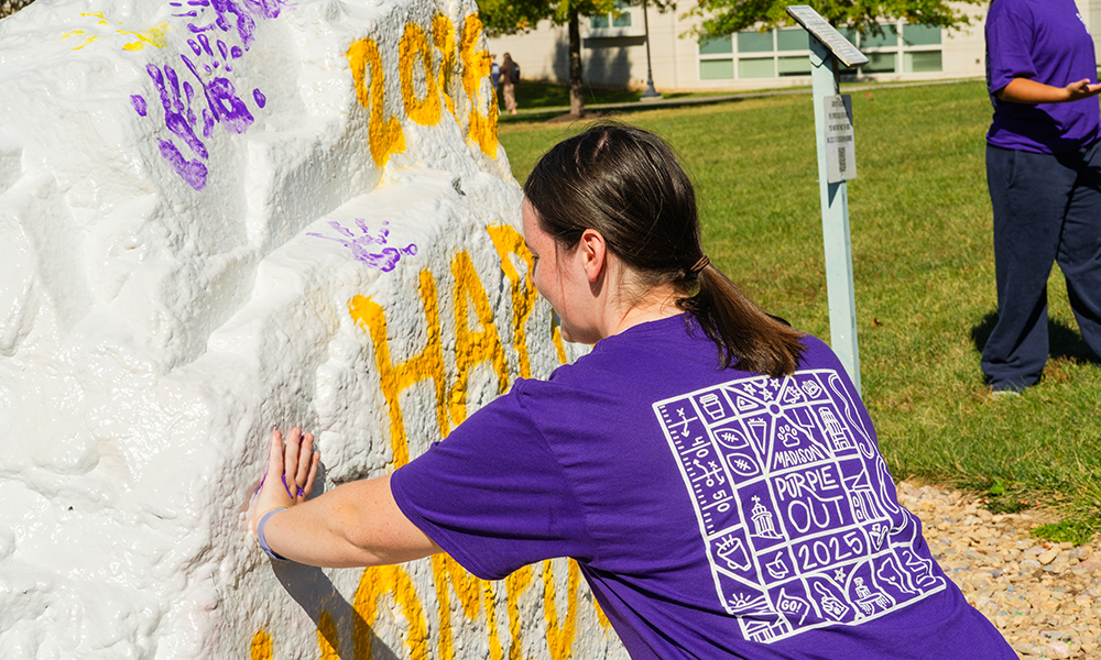 A Dukes paints the Spirit Rock wearing a purple T-shirt during Homecoming 2025