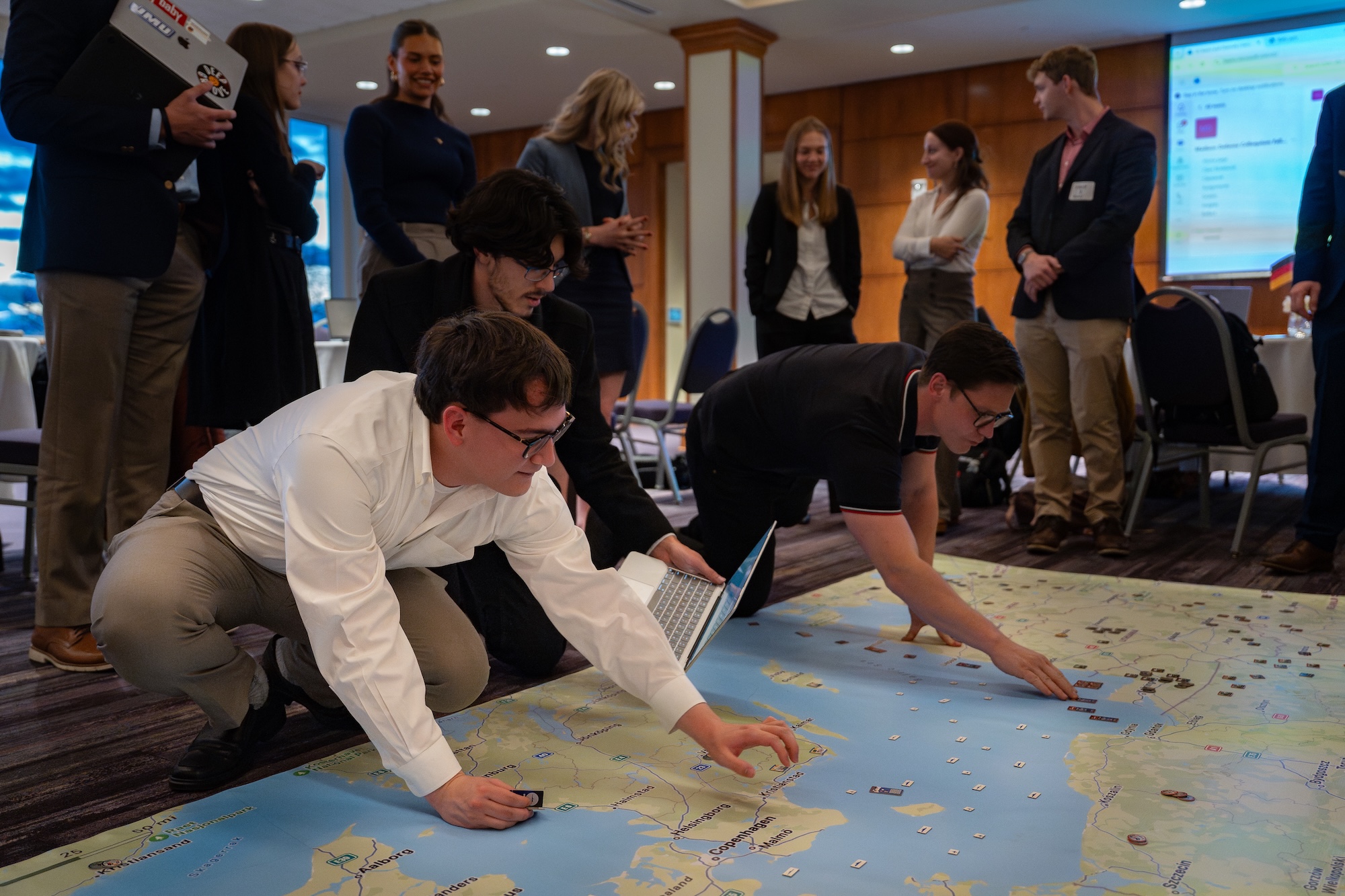 Participants engage collaboratively around a large map, analyzing data and strategizing during a workshop.