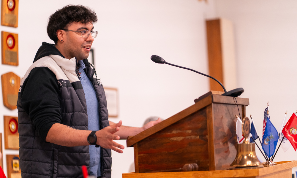 Alumnus Abraham Aponte speaks at the podium