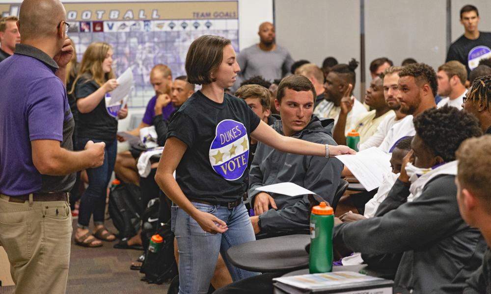 Members of Dukes Vote register JMU football players to vote.