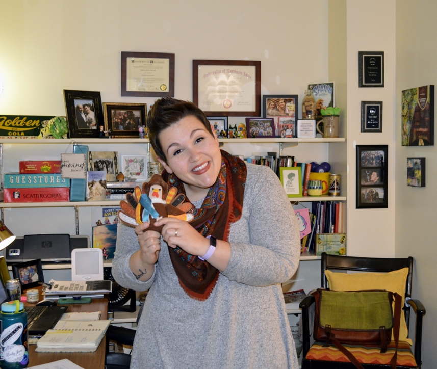 Woman smiles holding stuffed turkey who has a teal ribbon