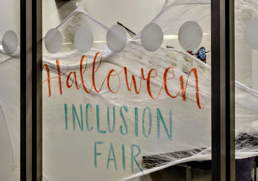 Window decorated with fake webs and words Halloween inclusion fair