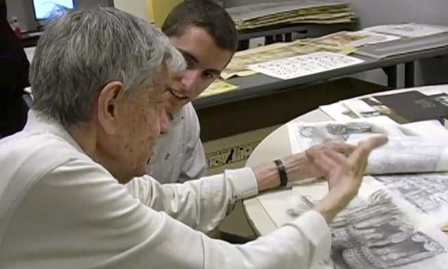 Josh Smead listens to Charles Lisanby with drawings on the table