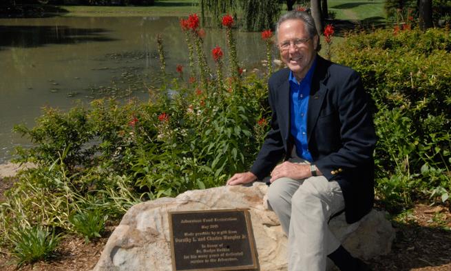 Photo of Norlyn Bodkin in arboretum at plaque honoring his service to JMU