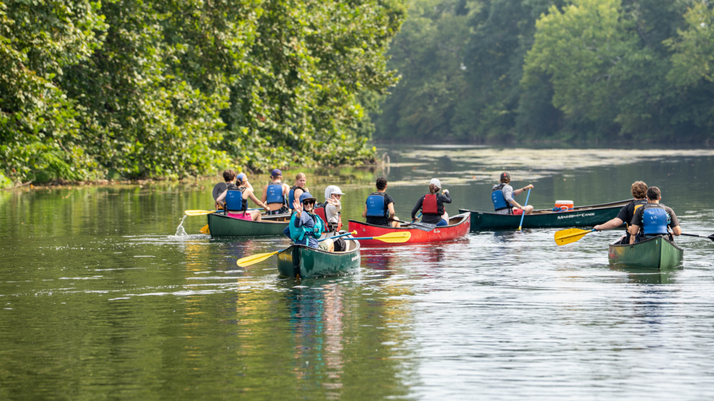 group of student canoeing down a river
