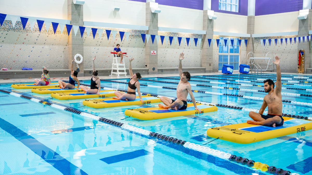 students stretching on stand up paddle board in the pool