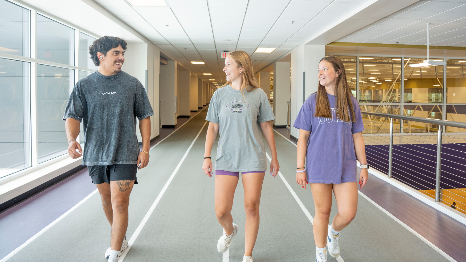 Three students walking on an indoor track