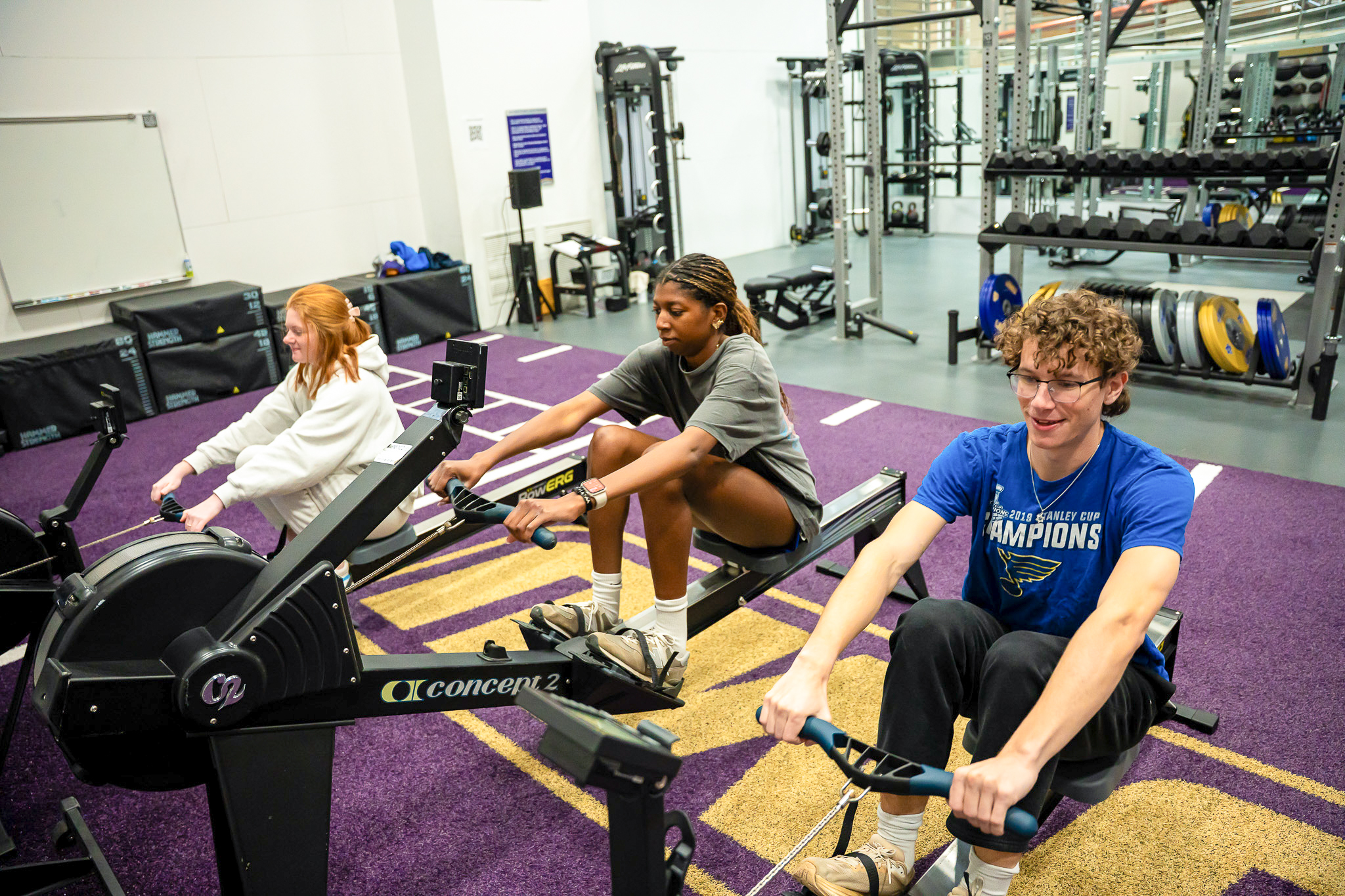three students using rowing machine in a functional training space