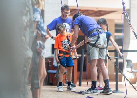 cmap counselor setting up camper to climb