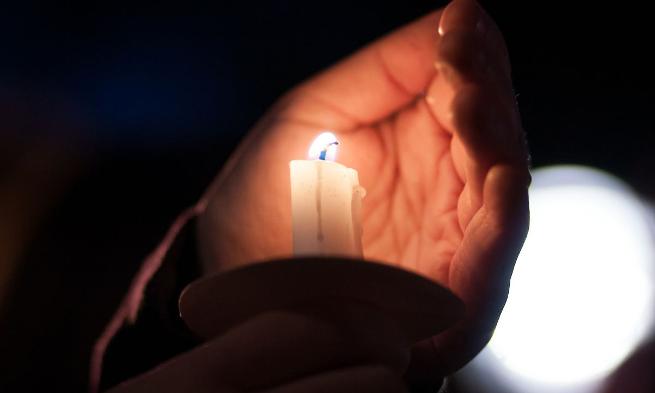 Closeup view of JMU student's hand holding candle as part of candlelighting ceremony