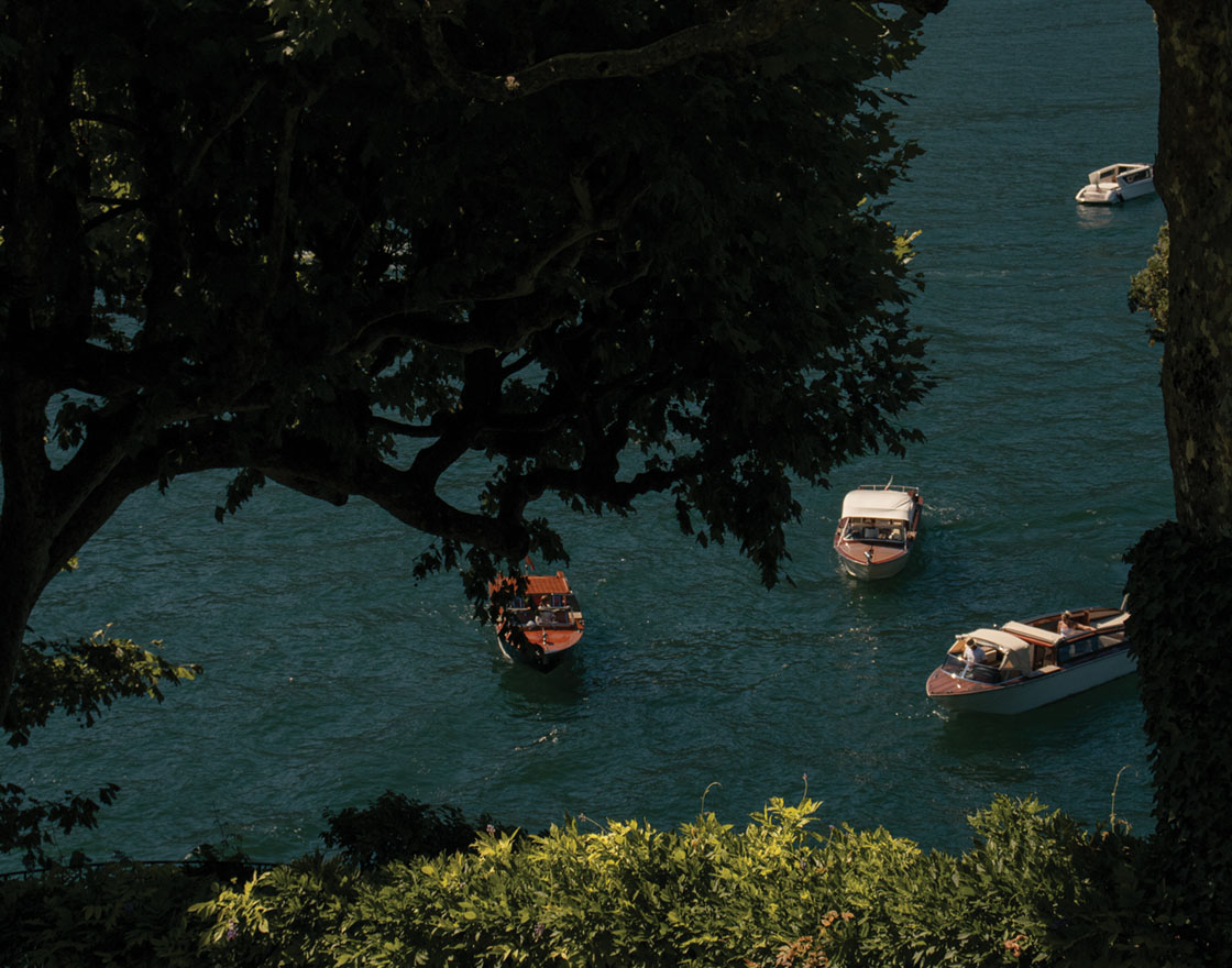 Boats floating on a calm lake, framed by lush greenery