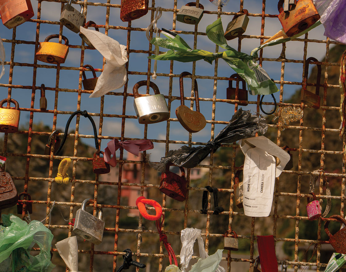 Metal fence featuring various colorful locks and tied ribbons