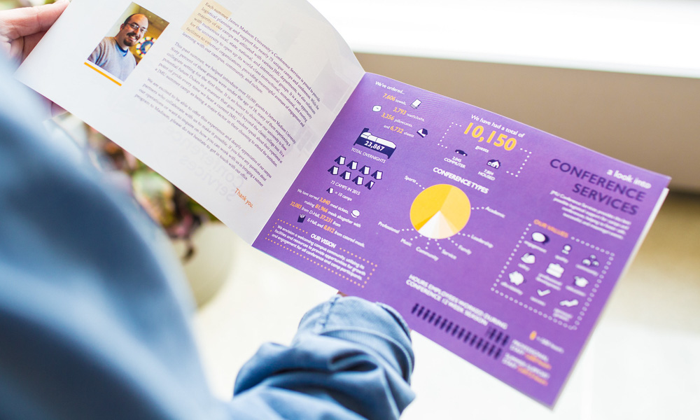 Someone holding a purple booklet. Only their hands are seen in the photo and the booklet has text, as well as infographics.
