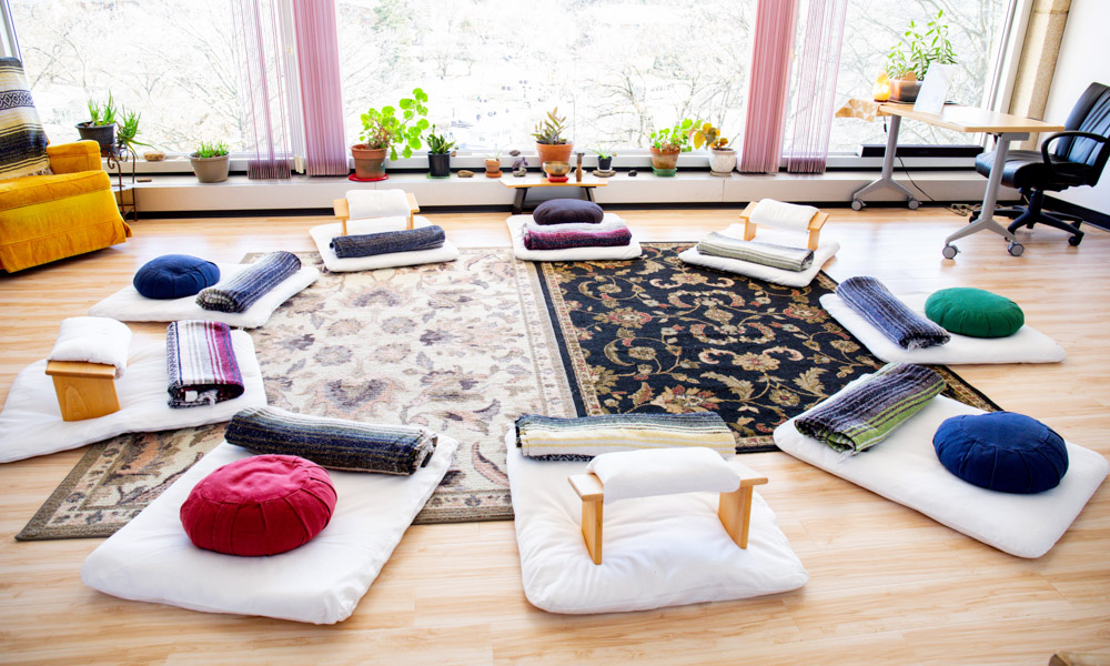 Photograph of meditation pillows and seats in a circle.