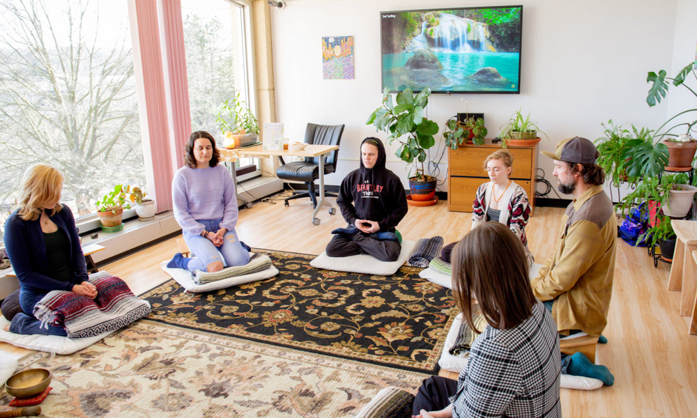 Photograph of a group of people sitting in a circle and meditating.
