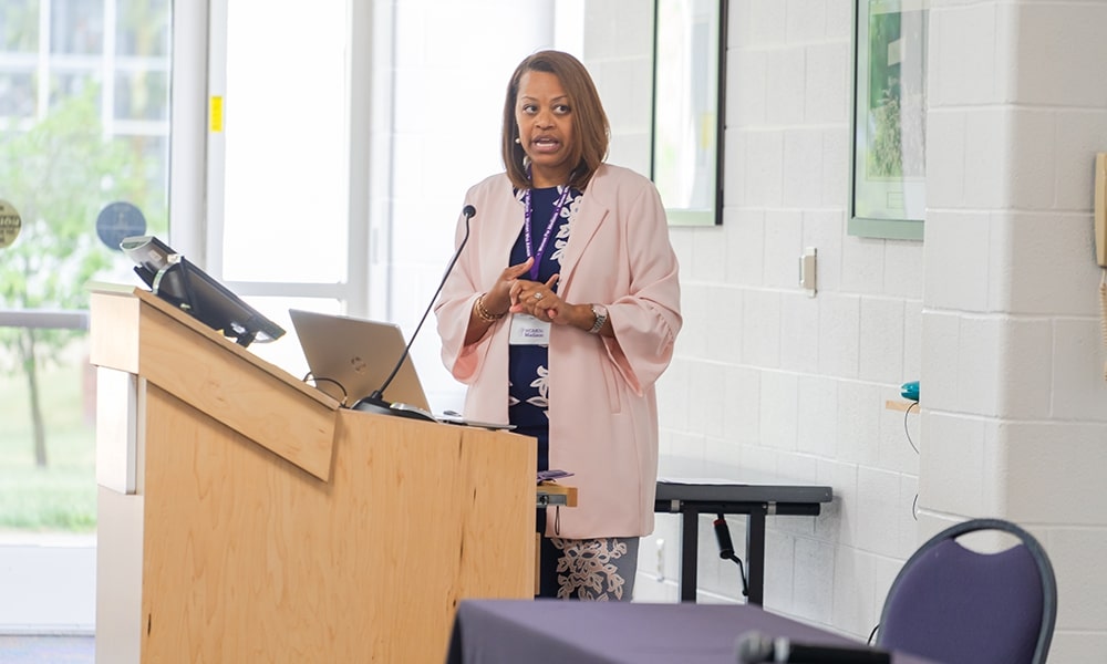 A speaker giving a presentation at a podium in a conference setting.