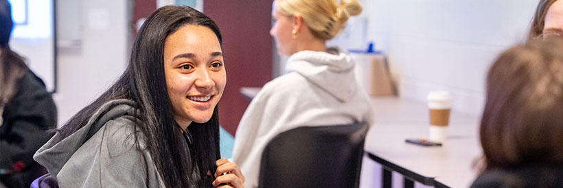 Image of a person smiling while looking at peers.