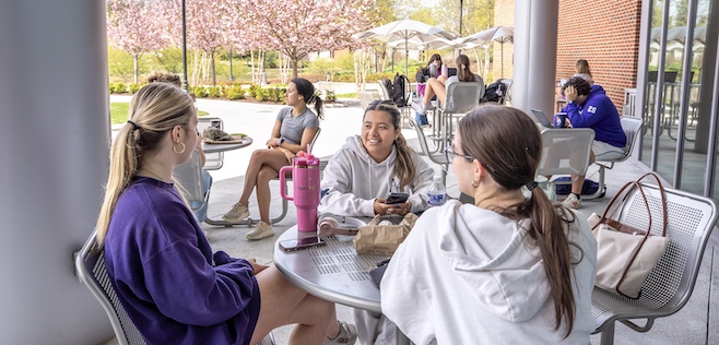 girls sitting around round table enjoying outdoor cafe area