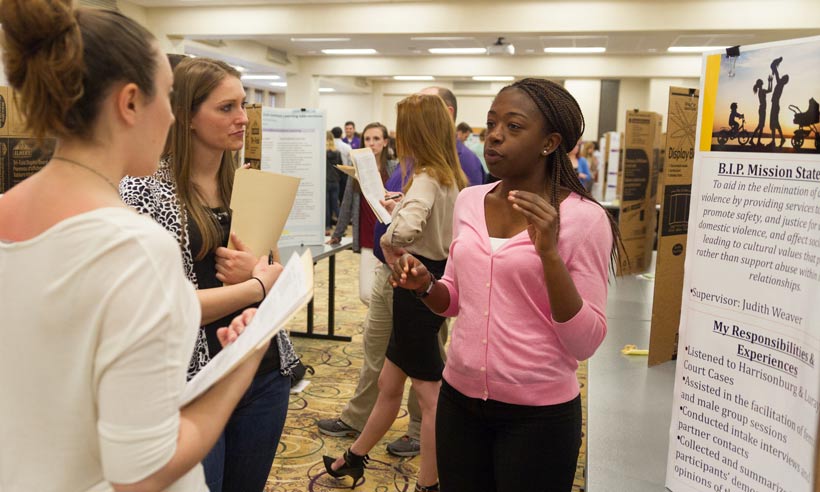 A JMU Psychology graduate student discusses her practicum experiences at a poster presentation