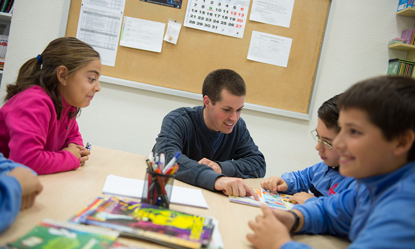 Male teacher and students looking at books