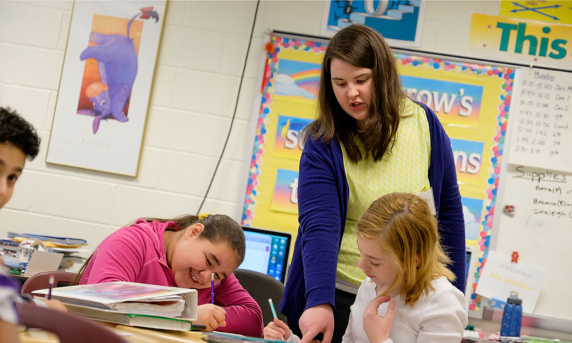 A student teacher works with middle school students in the classroom
