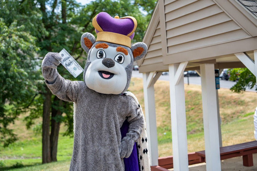 Duke dog posing with a hundred dollar bill