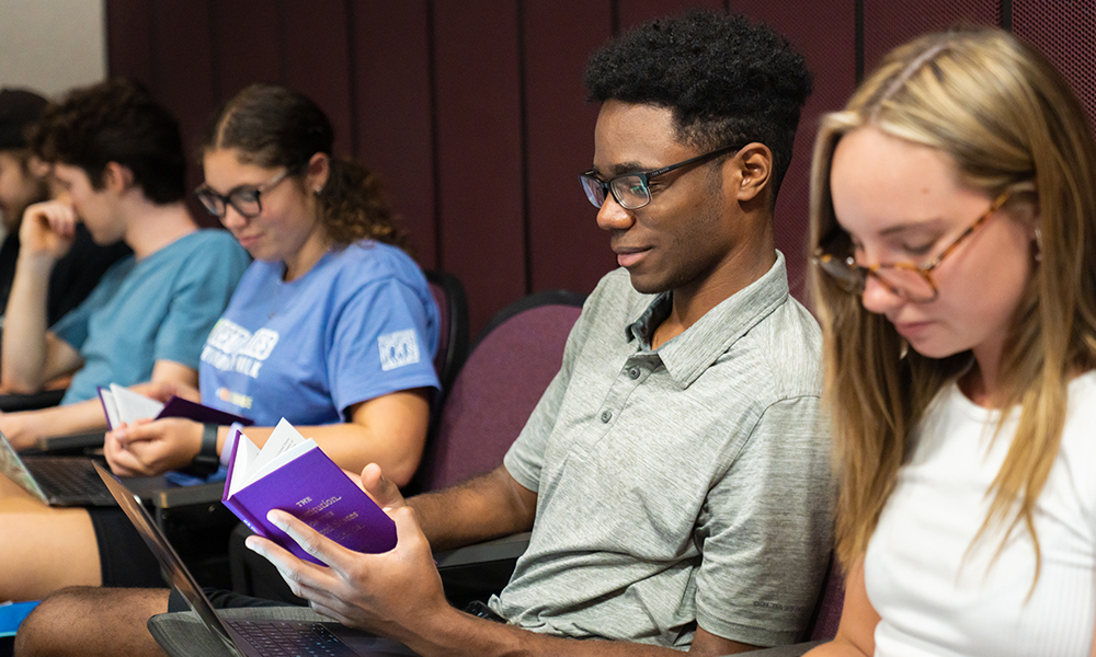 Students sit together and read Constitution books.