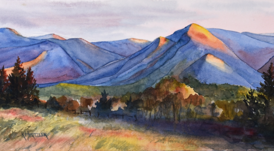 Watercolor painting of a mountainous landscape at sunset, featuring layers of blue mountains and colorful foliage in the foreground.