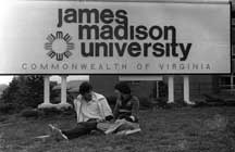Students sitting in front of a 1970's James Madison University sign