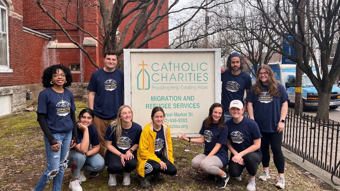 The 2022 ASB group poses in front of a Catholic Charities sign at their Louisville headquarters