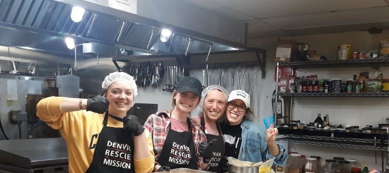 2022 Denver Rescue Mission participants pose in hairnuts and aprons while serving food
