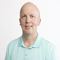 Dr. Jeff Batis, a man wearing a light blue polo shirt, smiling against a plain white background.