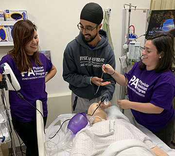 JMU students in a simulation lab practicing intubation procedures on a patient mannequin.
