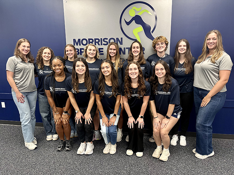 Group photo of the Morrison Recreation Center team for Fall 2025, featuring 15 smiling members in matching dark shirts, posing in front of a branded wall.