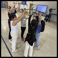 Children participating in a group activity using a hula hoop, promoting teamwork and physical activity.